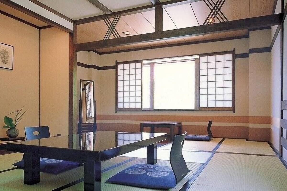 A traditional Japanese room with tatami flooring, a low table, and a sliding door.