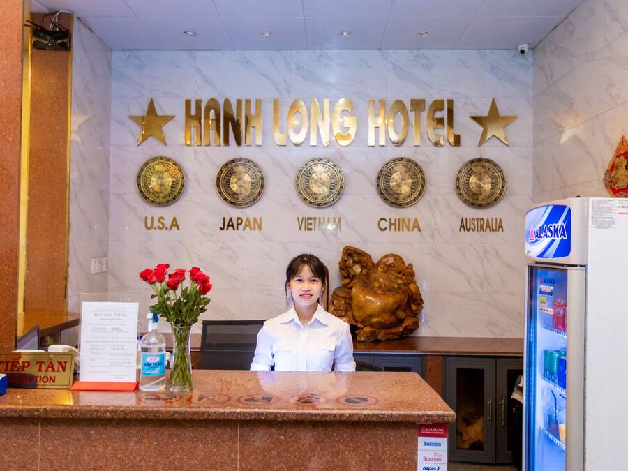 En hotellreception med en skylt som visar texten ”HANH LONG HOTEL” och flaggor som representerar USA, Japan, Vietnam, Kina och Australien.