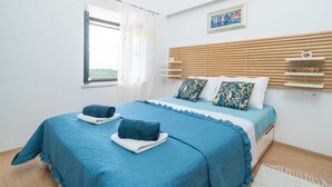 Une chambre à coucher avec un grand lit, une tête de lit en bois et une fenêtre ornée de rideaux légers.