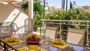 An outdoor dining area with a table set for four, surrounded by chairs, under a striped awning. - Los Aticos by Interhome (Dénia)