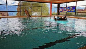 An indoor swimming pool with clear views of mountains through large windows. - Lilo/Studio by Interhome (Beatenberg)