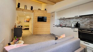 A modern kitchen with a stone backsplash, wooden ceiling, and a built-in TV. - Lilo/Studio by Interhome (Beatenberg)