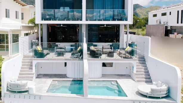 Une maison moderne à deux étages dotée d’un grand balcon, d’une piscine et offrant une vue sur la montagne.