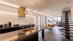 Une cuisine moderne dotée d’un îlot central, d’appareils électroménagers en acier inoxydable et d’un plan de travail noir.