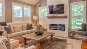 A living room with a sofa, a coffee table, a TV mounted on the wall, and a fireplace.