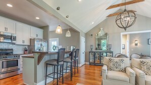 A spacious kitchen with modern appliances, a dining area with bar stools, and a cozy living room with a sofa and decorative pillows.