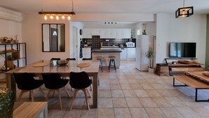 A modern kitchen with white cabinets, a central island, and a dining area with a table and chairs.