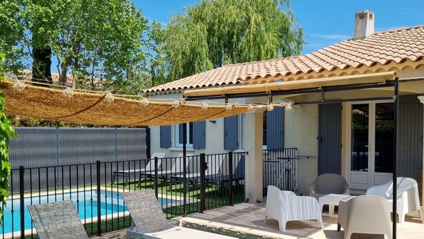 A backyard with a swimming pool, outdoor furniture, and a covered patio area.