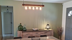 A dining area with a wooden table, black chairs, and a modern pendant light.