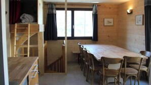 A wooden cabin with a dining area featuring a long table and multiple chairs. - No. 2, capacity: 14 people (Vars)