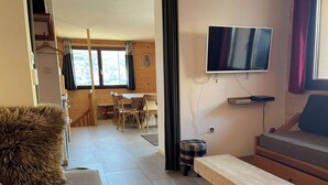 A cozy room with a wooden bench, a TV mounted on the wall, and a dining area with chairs and a table. - No. 2, capacity: 14 people (Vars)