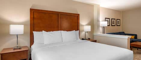 Una habitación de hotel con una cama grande, dos mesitas de noche, un escritorio, una silla y un sofá.