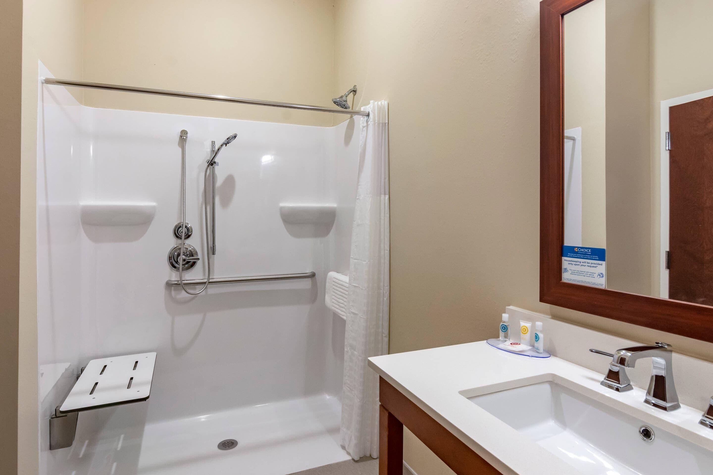 Un baño con ducha, lavabo, espejo y artículos de aseo.