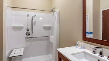 A bathroom with a shower, a sink, a mirror, and toiletries.
