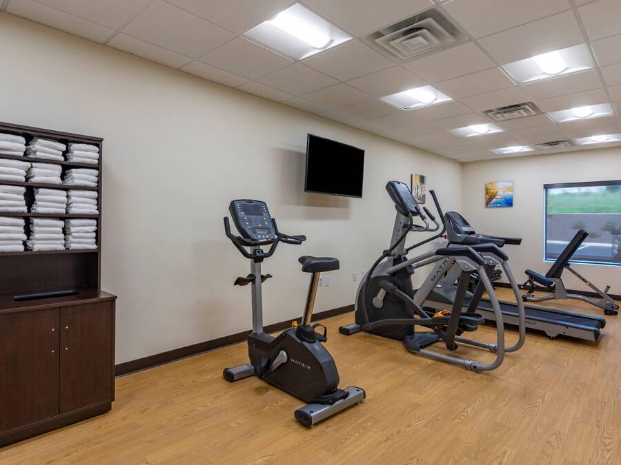 Un gimnasio con equipo de ejercicio, televisión y ventana con vistas.