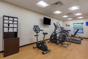 A gym with exercise equipment, a television, and a window with a view.