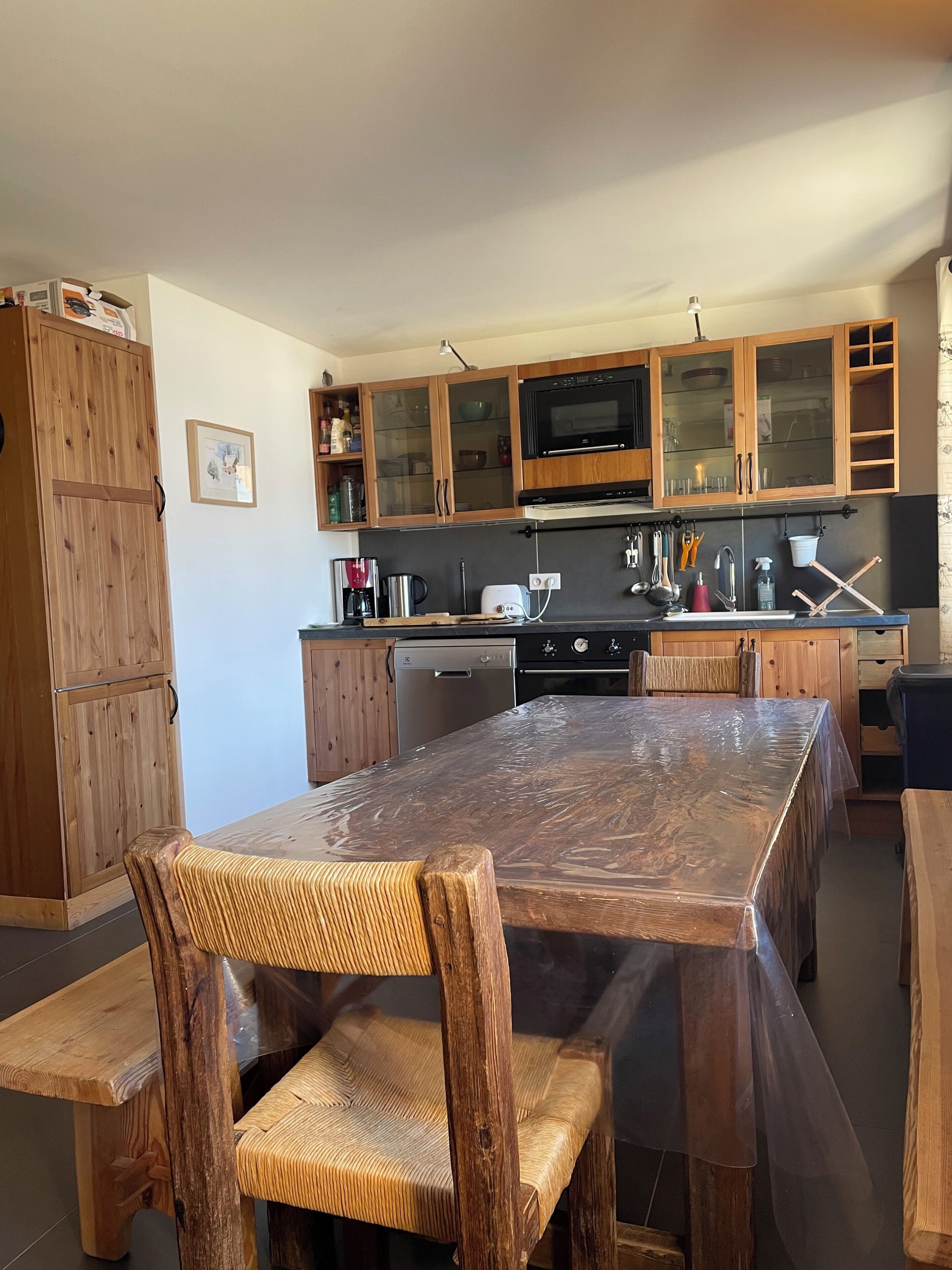 A kitchen with wooden cabinets, a microwave, a dishwasher, and a large dining table with chairs.