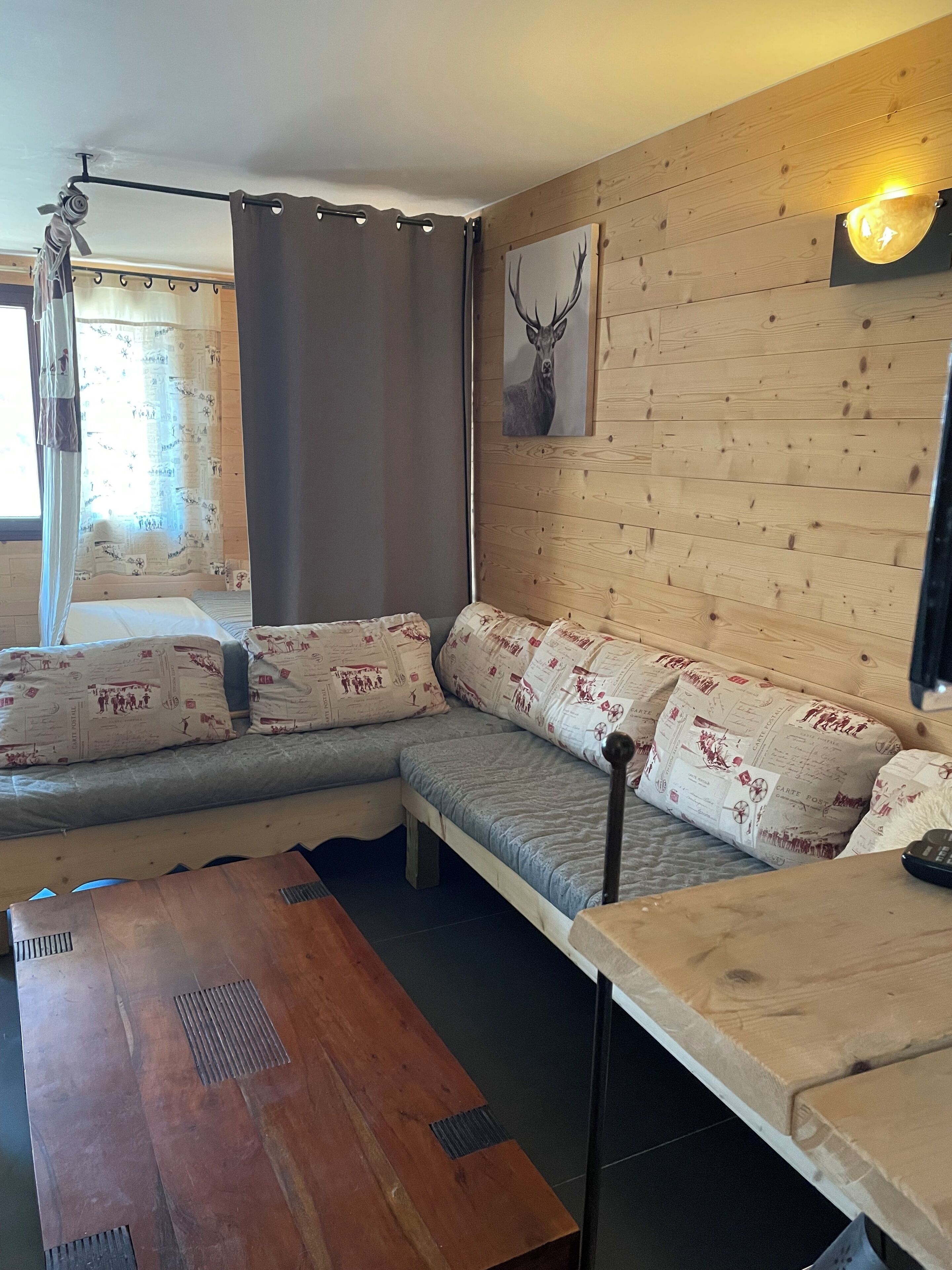 A cozy room with a wooden wall, a bed with patterned pillows, a bench, and a table.