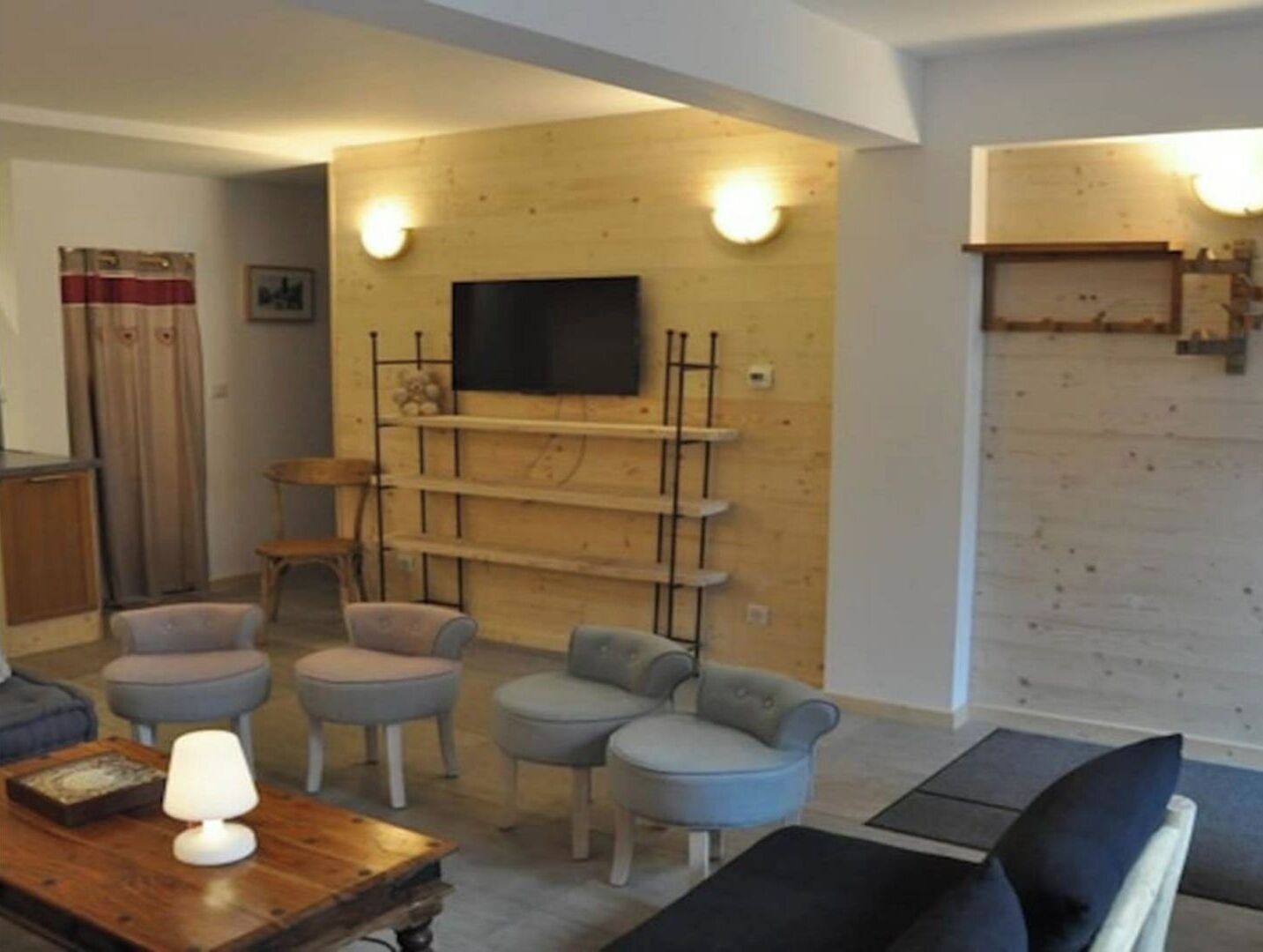 Un salon avec un mur en bois, un téléviseur fixé au mur et un canapé.