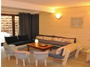 Un salon confortable avec un canapé, deux fauteuils, une table basse et une lampe.