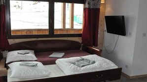A single bed with a wooden headboard, a flat-screen TV mounted on the wall, and a window with curtains. - No. 7, maximum 7 people (Vars)