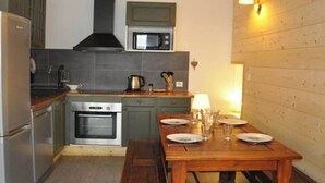 A compact kitchen with a microwave, oven, and a wooden dining table set for four. - No. 7, maximum 7 people (Vars)