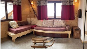 A cozy cabin interior with a wooden bench, a sofa with patterned cushions, and a wooden cart. - No. 7, maximum 7 people (Vars)