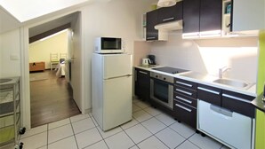 A compact kitchen with a microwave on top of a refrigerator, a built-in oven, and a sink with a faucet.