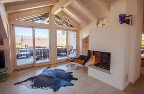 A spacious living room with a fireplace, large sliding glass doors to an outdoor patio, and a modern chandelier. - Atempause Vacation Apartment in Garmisch-Partenkirchen, Bavaria (Garmisch-Partenkirchen)