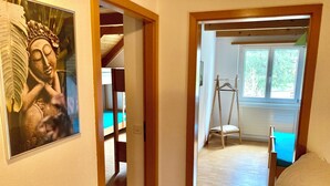 Ein Zimmer mit Bett, Hängesessel und einem Fenster mit Blick auf Grünflächen.