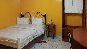 A single-bed room with a wooden headboard, a small bedside table, and a chair. - Garden of Favour Resort (Naivasha)