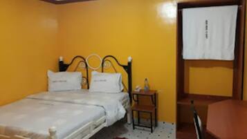A single-bed room with a wooden headboard, a small bedside table, and a chair.