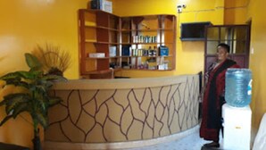 A reception area with a curved counter, a water dispenser, and a bookshelf. - Garden of Favour Resort (Naivasha)