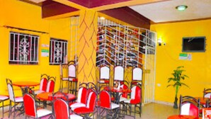 A room with yellow walls, red and white chairs, and tables. - Garden of Favour Resort (Naivasha)