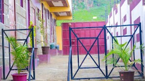 A courtyard with a tiled floor, potted plants, and a metal gate. - Garden of Favour Resort (Naivasha)