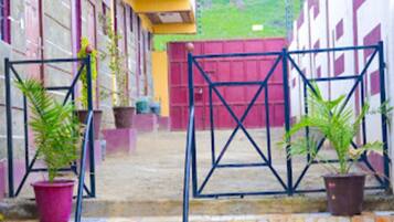 A courtyard with a tiled floor, potted plants, and a metal gate.