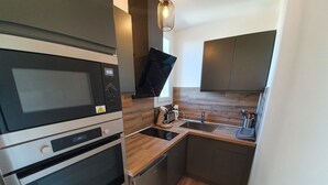 A compact kitchen with a built-in oven, microwave, and sink.