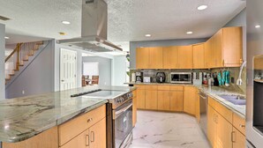 Une cuisine moderne avec des meubles en bois, un four encastré, un four à micro-ondes et un plan de travail en granit.