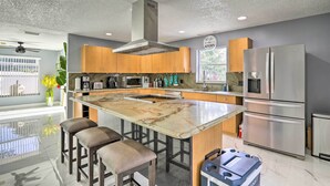 Une cuisine moderne dotée d’un grand îlot central, d’appareils électroménagers en acier inoxydable et d’armoires en bois.