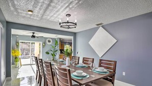 Un espace repas doté d’un sol en marbre, de chaises en bois, d’un lustre et d’un décor mural moderne.