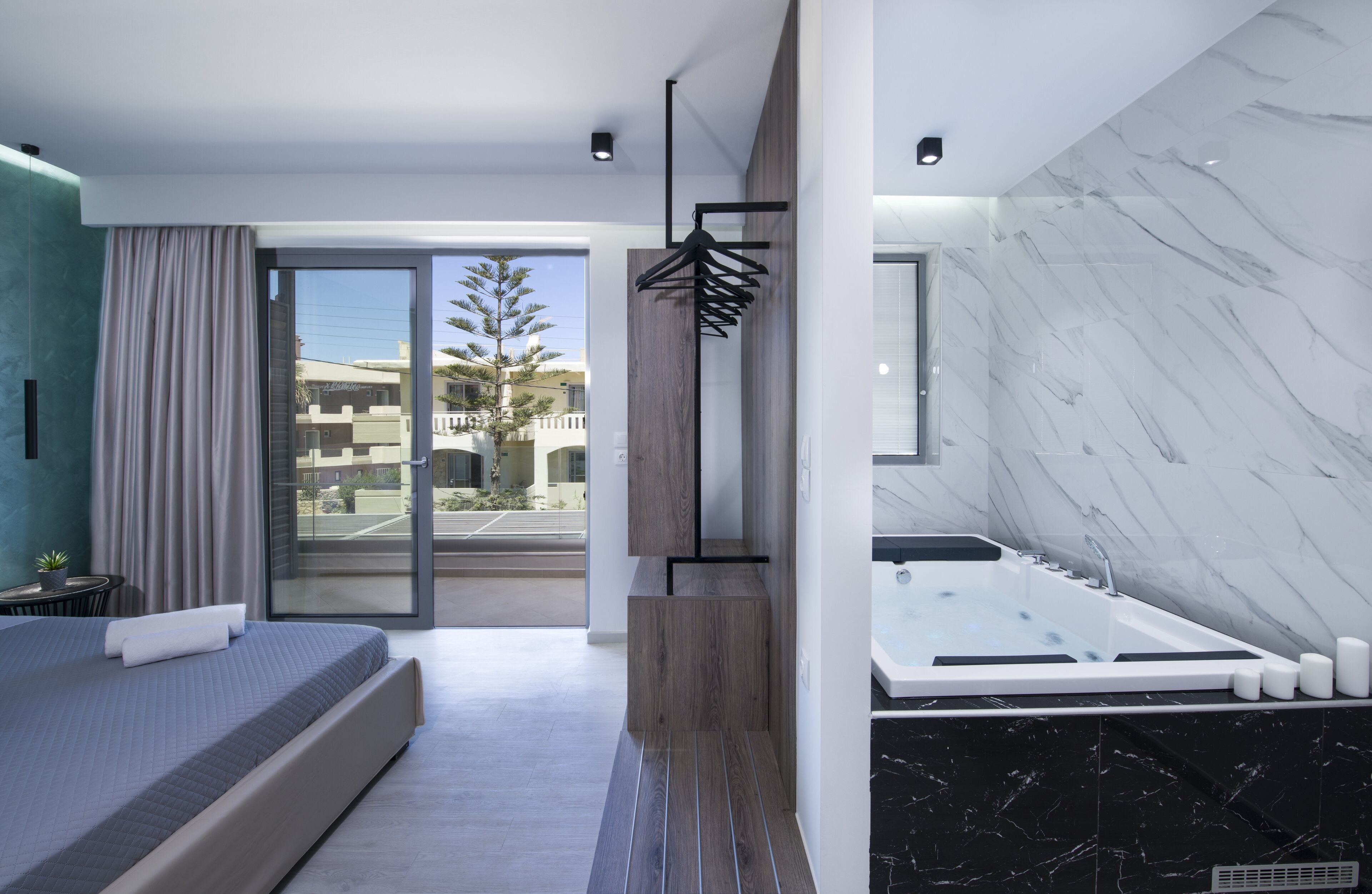 A modern hotel room with a large bed, a bathroom with a jacuzzi, and a view of the outside.
