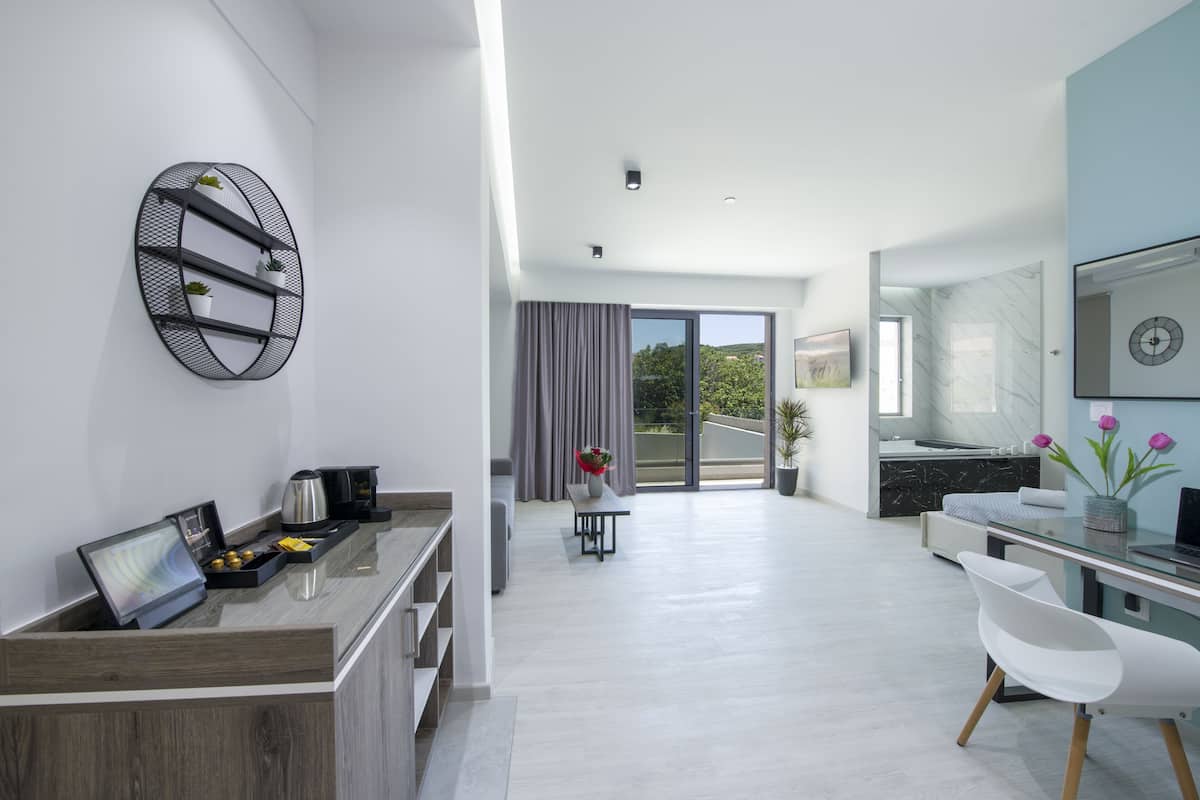Una habitación de hotel moderna con cocina, una mesa de comedor y un balcón con cortinas.