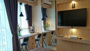 Une chambre d’hôtel comprenant un lit, un bureau avec deux chaises, un téléviseur fixé au mur et la climatisation.
