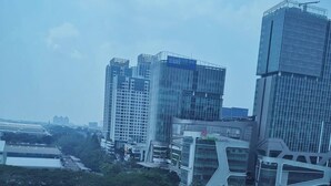 Une vue urbaine avec des immeubles modernes de grande hauteur, un pont et une route où circulent des véhicules.