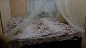 A bed with a floral bedspread and a white canopy. - Tala Village Inn (Tala)