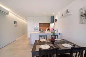 A modern kitchen with white cabinets, a central island, and a dining area with a table set for two.