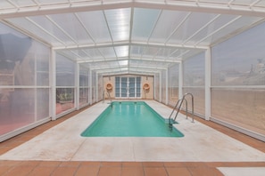 A covered swimming pool with glass walls, a tiled floor, and a clear view of the surrounding area. - Holiday Home 'Puerta Marina Costa de la Luz' close to the Sea with Shared Pool (La Redondela (Isla Cristina))