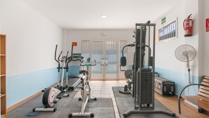 A gym with exercise equipment, a bench, a fan, and a fire extinguisher.