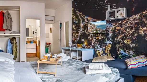 A room with a bed, a desk, and a chair. There is a wall with a mural and a window. - Lovely Bed and Breakfast in Center of Sorrento (Sorrento)