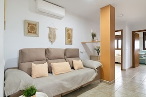 A living room with a sofa, wall decor, and a hallway leading to another room.
